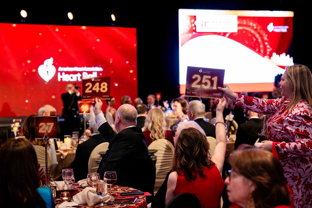 Man holding up bidder paddle 248 while woman seated behind him holds up number 251.